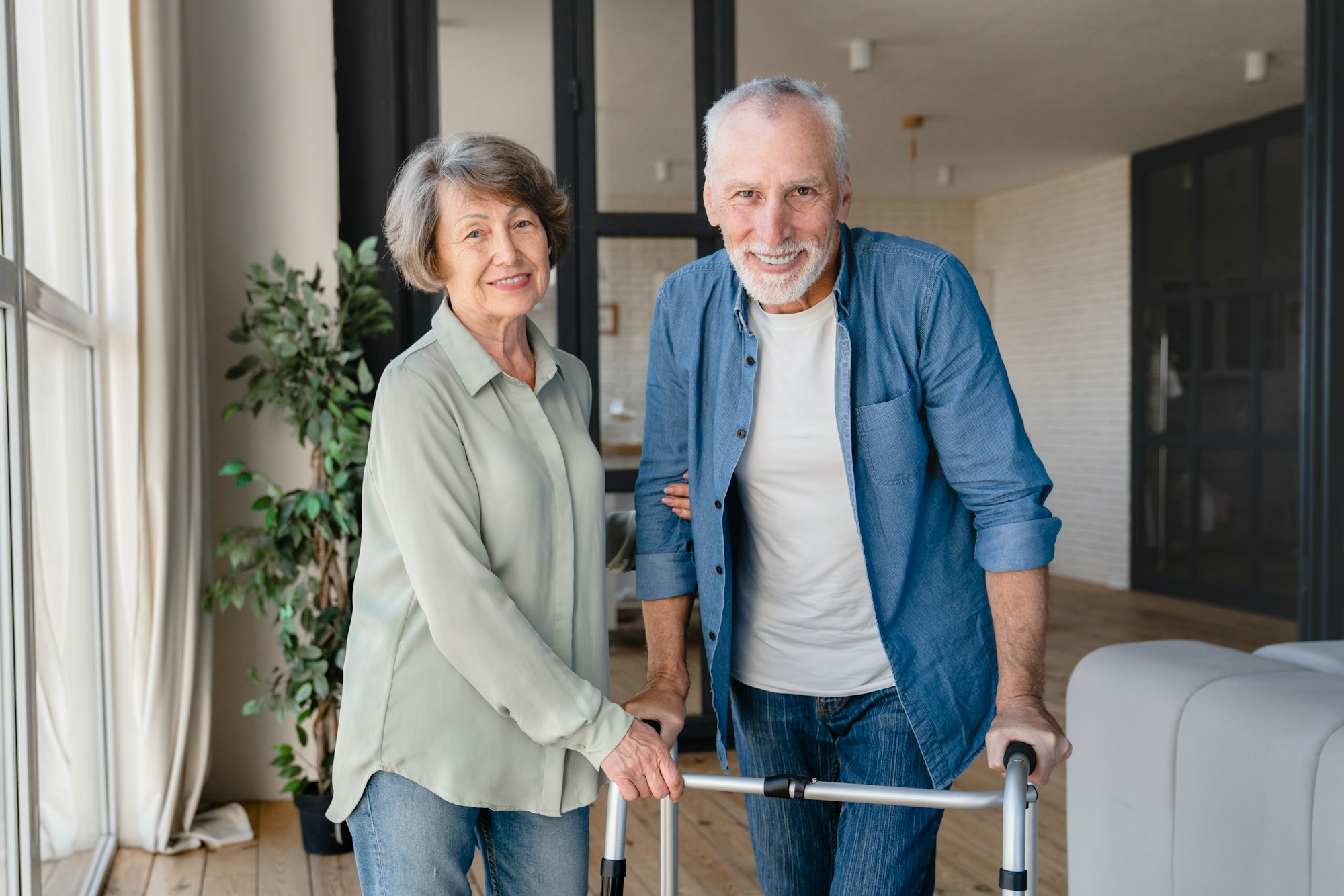 Happy couple looking at camera. Disabled incapacitated handicapped old elderly husband using walker